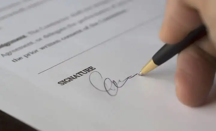 Hand signing a contract at the signature line