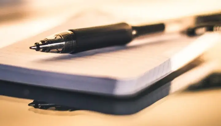 Fountain pen resting on a lined pocket notebook