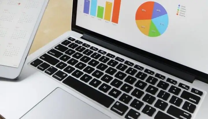 Laptop showing bar and pie charts beside a tablet calendar