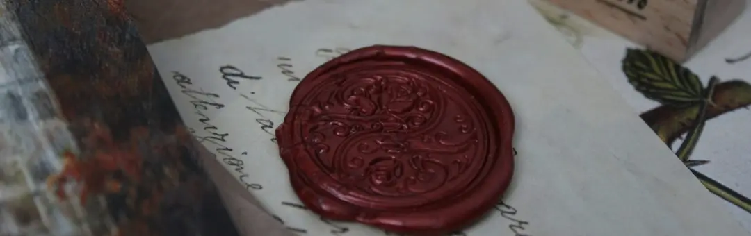Dark red wax seal pressed onto a handwritten letter
