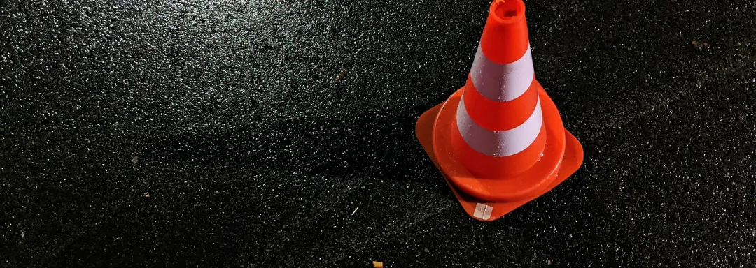 Orange traffic cone on wet asphalt at night