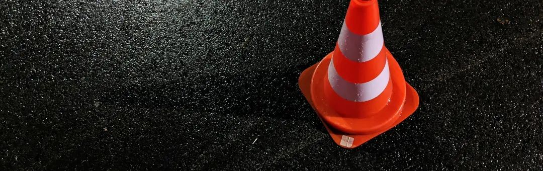 Orange traffic cone on wet asphalt at night