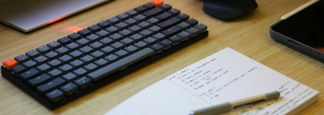 Notepad with a handwritten checklist beside a keyboard