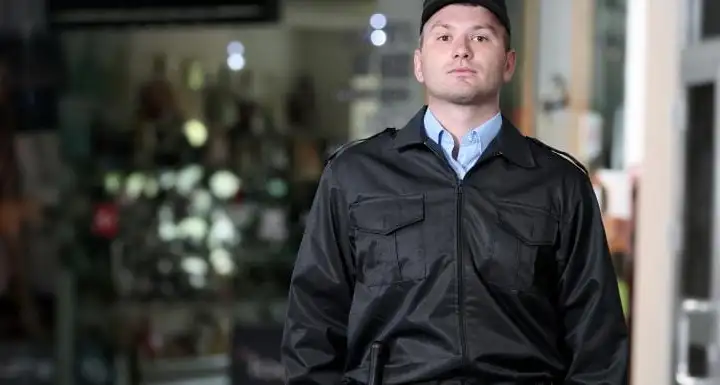Security guard in a black uniform standing at the entrance of a retail store