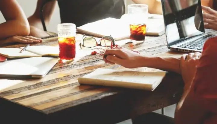 Team working together at a table with laptops and notebooks