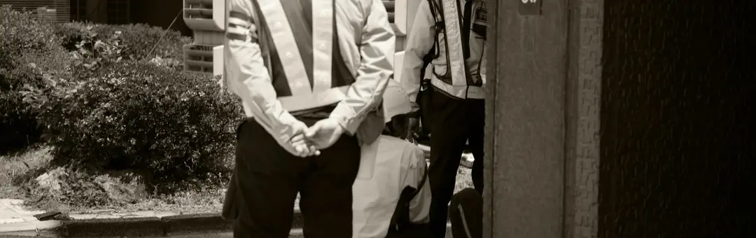 Two men in hard hats and reflective vests watching over a construction site entrance