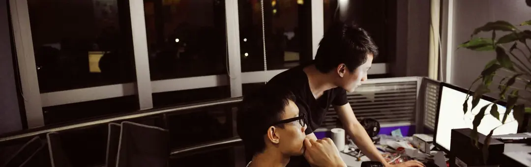 Two men working at computers in an office at night